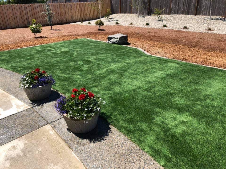 A finished yard by Carrillo's Yard Work with artificial turf, mulch beds and new plantings